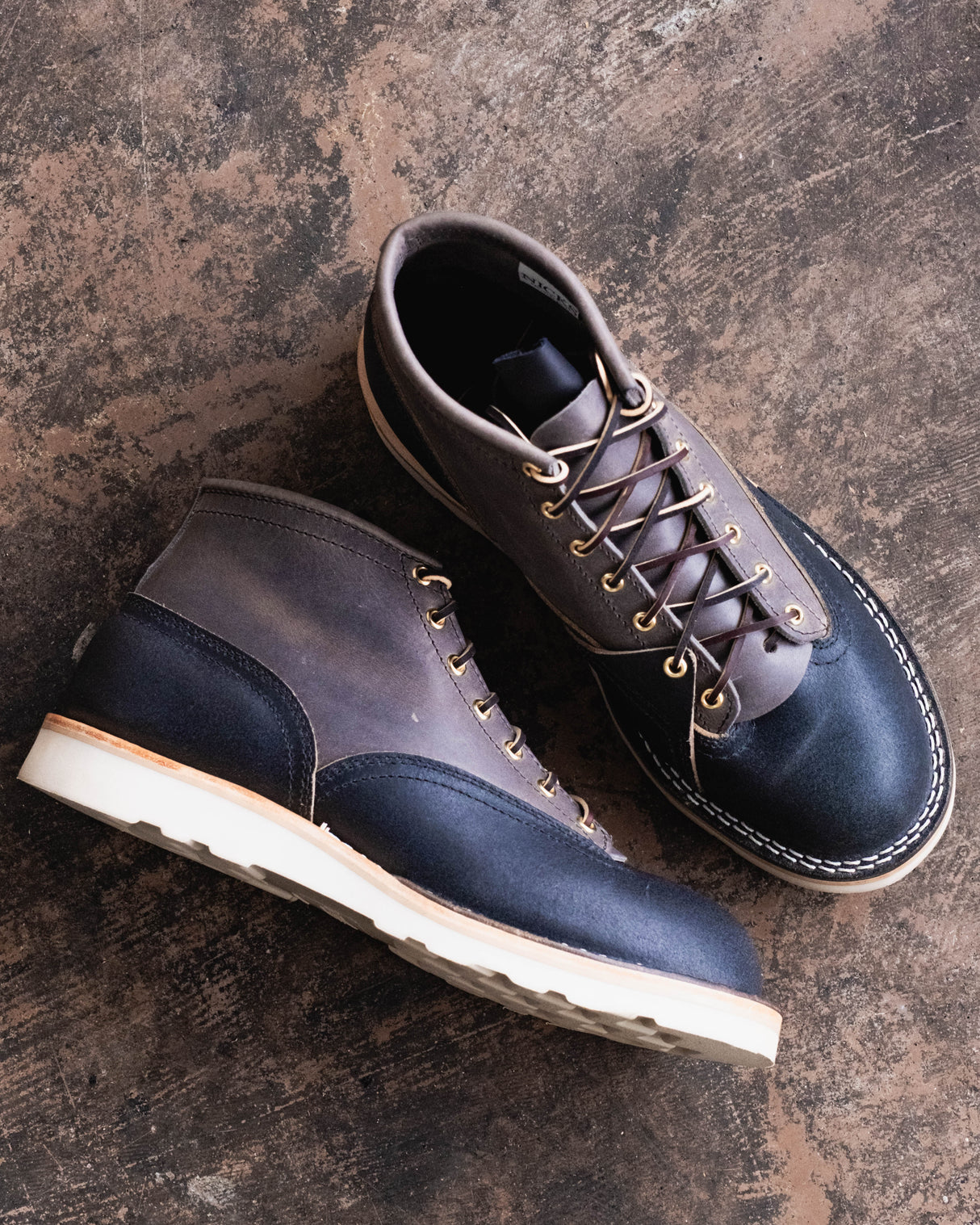 Pair of brown leather shoes with white soles on a textured surface