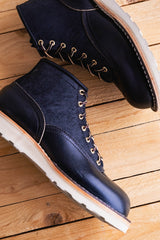 Pair of blue suede boots with white soles on a wooden floor