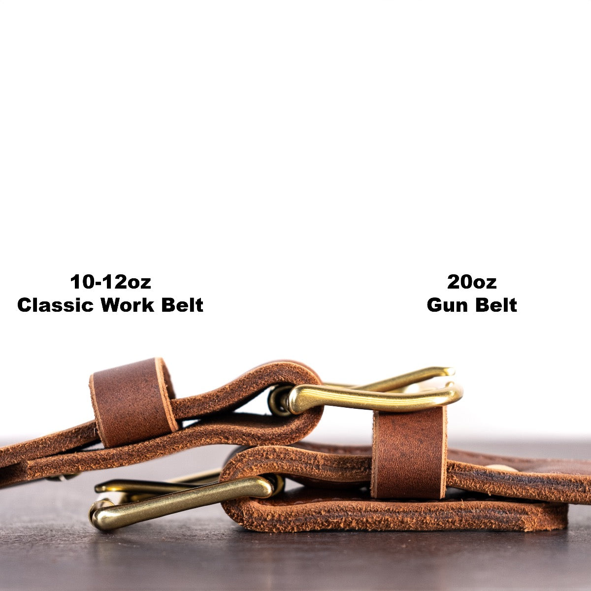 Two brown belts with brass hardware sitting on top of each other showing the thicknesses of both belts. There are two captions telling what the thickness is. The belt on the left is 10-12oz and the belt on the right os 20oz. 