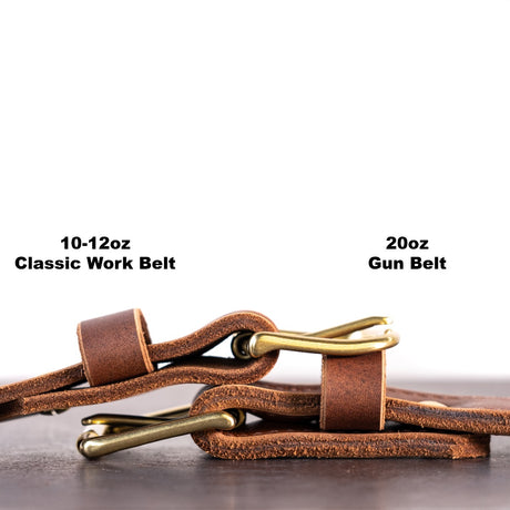 Two brown belts with brass hardware sitting on top of each other showing the thicknesses of both belts. There are two captions telling what the thickness is. The belt on the left is 10-12oz and the belt on the right os 20oz. 