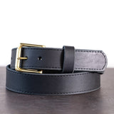 Brown belt with brown stitching and brass hardware sitting on metal surface with white background