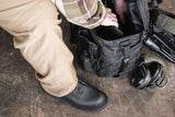 Black boots with Khaki pants.  Black duffle bag.  Green ear phones on ground.