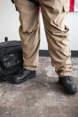 Person in Black boots with Khaki pants.  Black duffle bag.  American Flag in Background.
