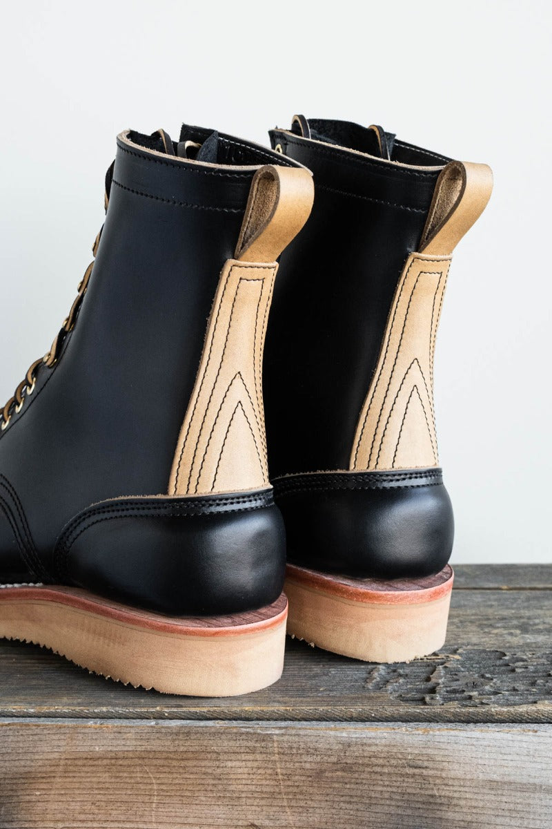 Black eight inch boot with tan backstay and vibram foam wedge sole.