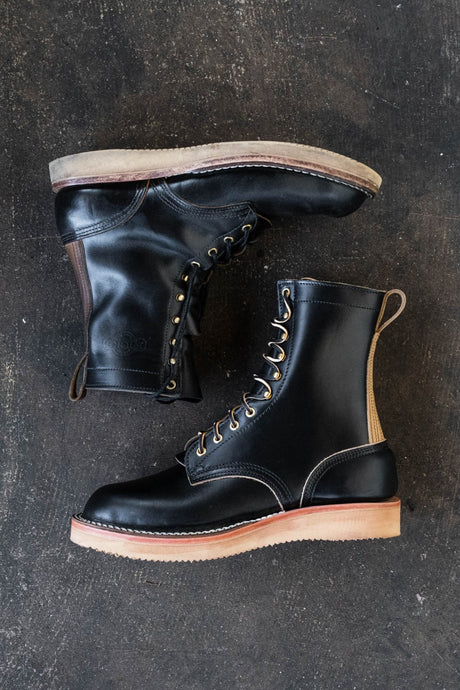 Black eight inch boot with tan backstay and vibram foam wedge sole.