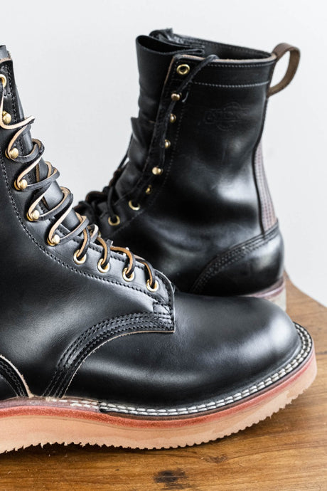 Black eight inch boot with tan backstay and vibram foam wedge sole.