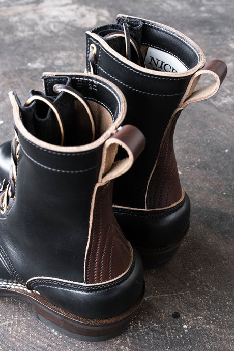 Eight inch tall black leather boot with brown backstay with a rubber sole.