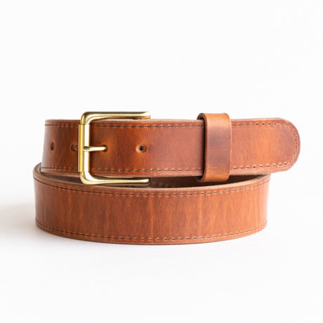 Close-up of a natural leather belt with a smooth finish, featuring a simple brass buckle and visible grain details, showcasing its timeless and rustic craftsmanship.